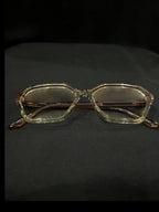 OPTICA geometric octagonal eyeglasses in translucent light brown acetate with angular frames and subtle brown lenses.