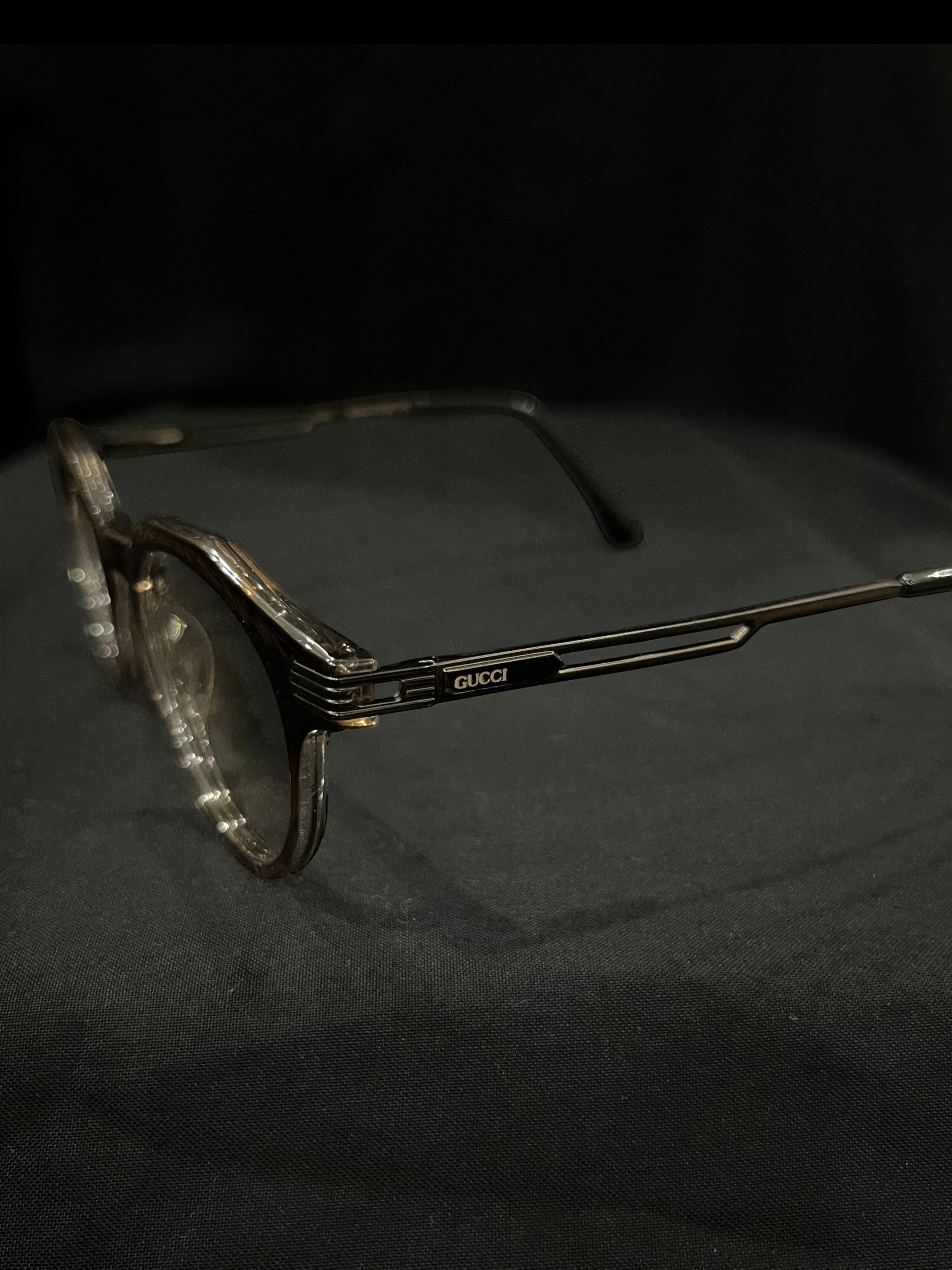 OPTICA Kocka round eyeglasses with black kitty corner accents and Gucci logo on the temples. Clear lenses and a black and white plastic frame.